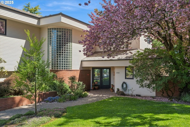 exterior space with french doors, a lawn, and brick siding
