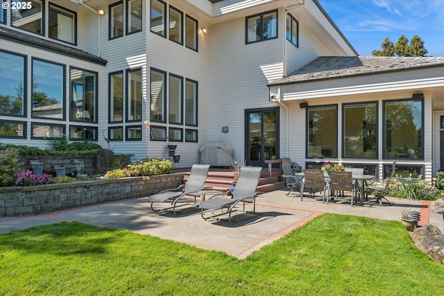 rear view of house with a lawn and a patio