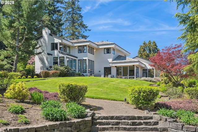 back of house with a lawn, a chimney, and a sunroom