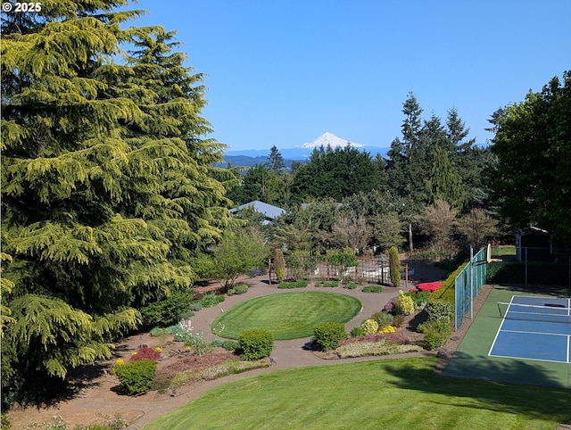 view of community with a lawn, a mountain view, and fence