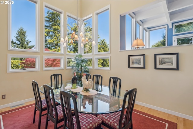 dining area with visible vents, baseboards, wood finished floors, and beamed ceiling