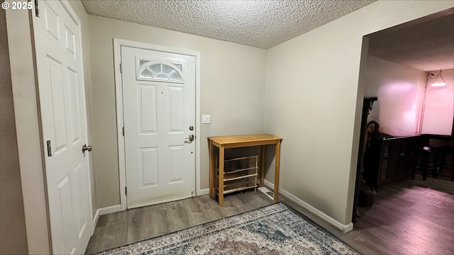 entrance foyer featuring a textured ceiling, baseboards, and wood finished floors