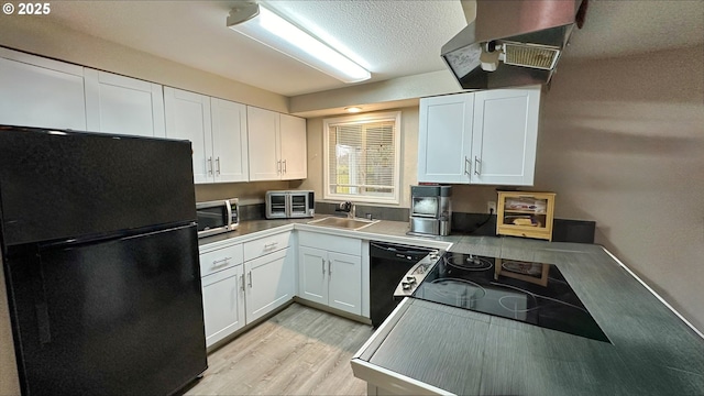 kitchen featuring range hood, light wood finished floors, white cabinets, a sink, and black appliances