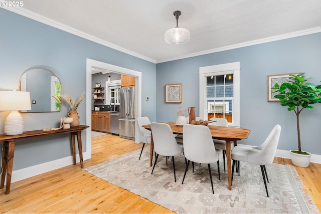 dining space featuring ornamental molding, light wood-style flooring, and baseboards