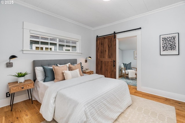bedroom with a barn door, crown molding, wood finished floors, and baseboards