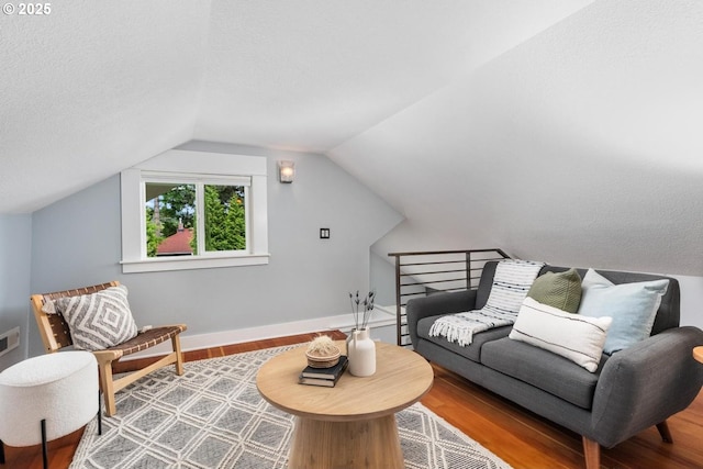 living area with wood finished floors, vaulted ceiling, and baseboards