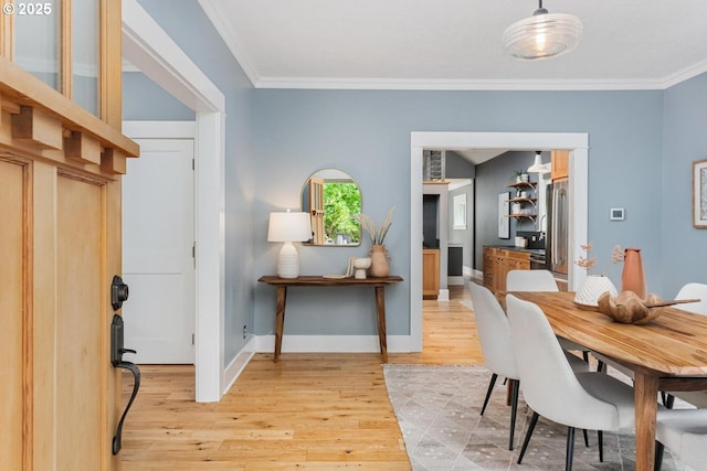 dining space featuring light wood-style flooring, ornamental molding, and baseboards