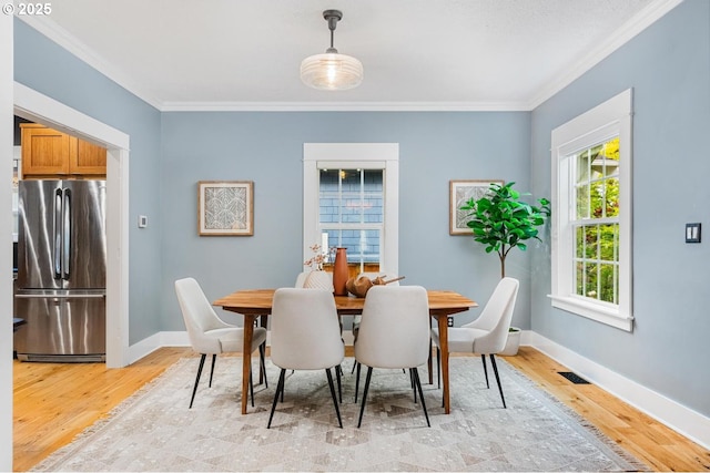 dining space with crown molding, light wood-type flooring, and baseboards