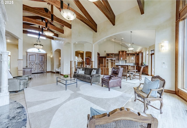 living area featuring light wood-type flooring, high vaulted ceiling, arched walkways, and beamed ceiling