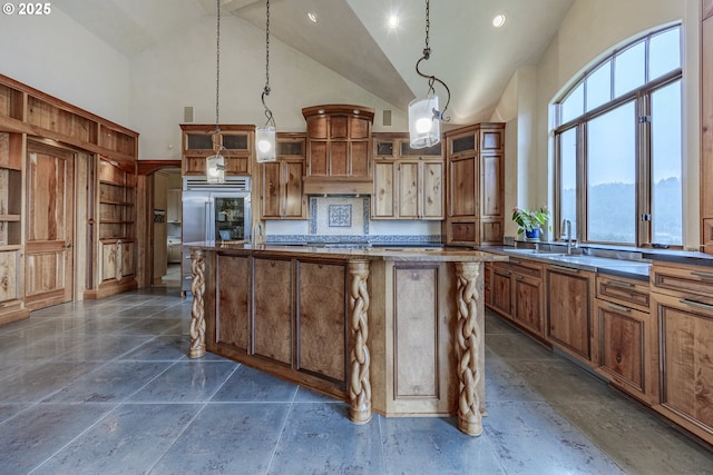 kitchen featuring brown cabinetry, glass insert cabinets, a center island, hanging light fixtures, and high vaulted ceiling