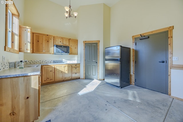 kitchen featuring pendant lighting, light countertops, freestanding refrigerator, a sink, and black microwave