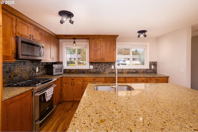 14424 SE Bevington Ct, Milwaukie, OR 97267 - kitchen with stainless steel appliances, brown cabinets, decorative backsplash, and light stone counters