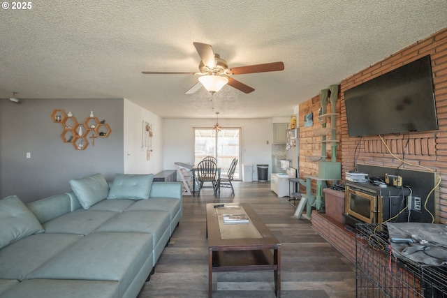 living area with a wood stove, a textured ceiling, dark wood finished floors, and a ceiling fan