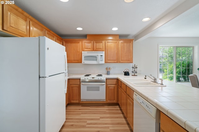 kitchen featuring a sink, light wood-style floors, white appliances, recessed lighting, and a peninsula