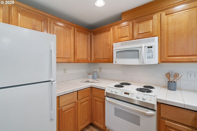 kitchen with recessed lighting, tile counters, and white appliances