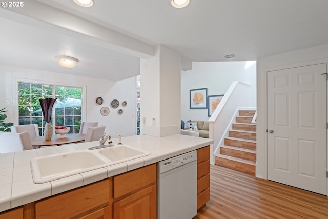 kitchen featuring white dishwasher, a sink, open floor plan, recessed lighting, and light wood-style flooring