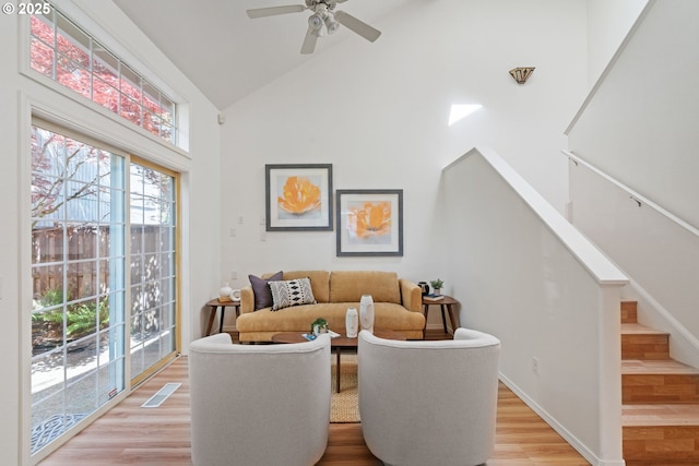 living area featuring visible vents, ceiling fan, high vaulted ceiling, stairway, and light wood-type flooring