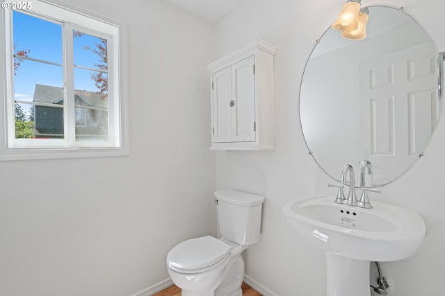 half bath featuring baseboards, a sink, and toilet