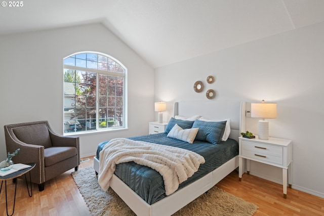 bedroom with baseboards, lofted ceiling, and light wood-type flooring