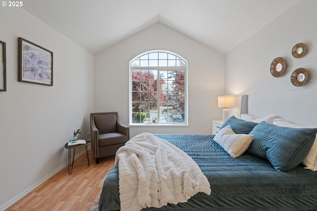 bedroom featuring baseboards, vaulted ceiling, and wood finished floors