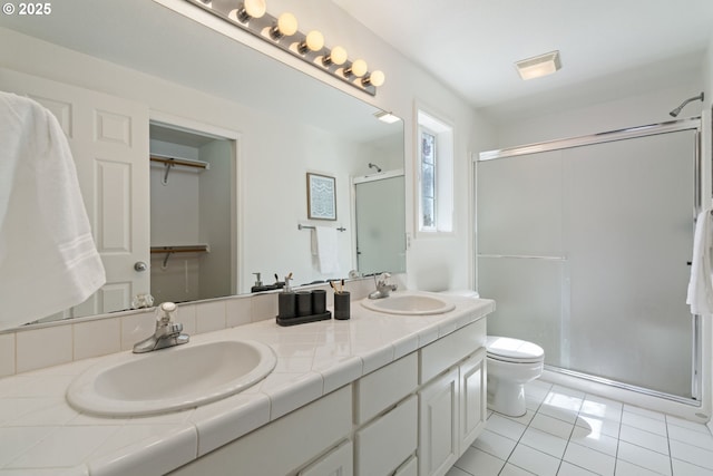 full bathroom featuring double vanity, toilet, a sink, and a stall shower