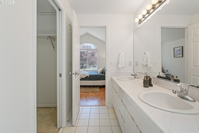 ensuite bathroom featuring a sink, tile patterned floors, ensuite bath, and double vanity