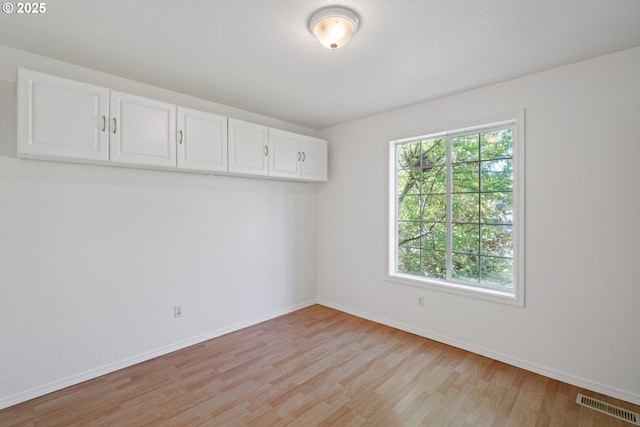 unfurnished room featuring baseboards, visible vents, and light wood-style flooring