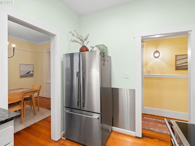 2127 NW Irving St Unit 104, Portland, OR 97210 - kitchen featuring freestanding refrigerator, wood-type flooring, crown molding, baseboards, and dark countertops