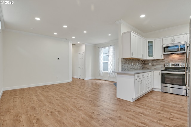 kitchen featuring appliances with stainless steel finishes, ornamental molding, open floor plan, decorative backsplash, and light countertops