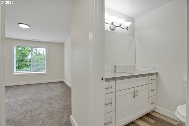 bathroom with toilet, baseboards, vanity, and a chandelier
