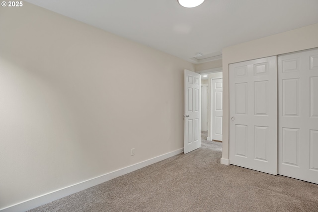 unfurnished bedroom featuring carpet floors, baseboards, and a closet