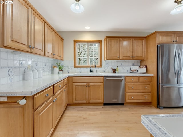 kitchen featuring sink, decorative backsplash, light wood-type flooring, and appliances with stainless steel finishes