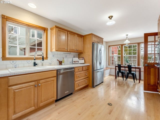 kitchen featuring light hardwood / wood-style flooring, hanging light fixtures, tasteful backsplash, appliances with stainless steel finishes, and sink