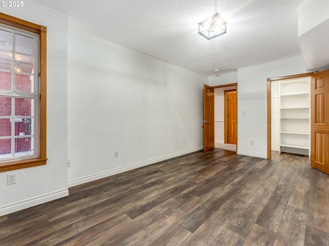 unfurnished bedroom with a closet, a spacious closet, and dark hardwood / wood-style floors