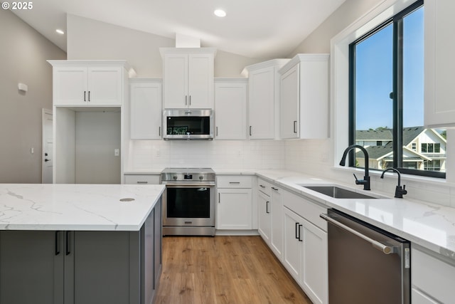 559 Meadows Dr, Manzanita, OR 97130 - kitchen featuring appliances with stainless steel finishes, a sink, vaulted ceiling, backsplash, and white cabinetry
