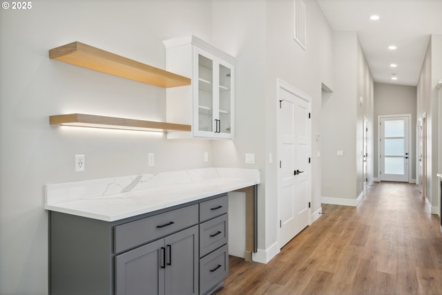 559 Meadows Dr, Manzanita, OR 97130 - kitchen with open shelves, gray cabinets, light wood-style flooring, baseboards, and glass insert cabinets