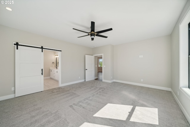 559 Meadows Dr, Manzanita, OR 97130 - unfurnished bedroom featuring light carpet, a barn door, baseboards, ensuite bath, and ceiling fan