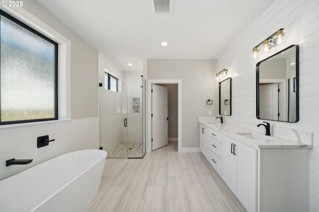 559 Meadows Dr, Manzanita, OR 97130 - full bathroom featuring a shower stall, double vanity, a freestanding tub, recessed lighting, and baseboards