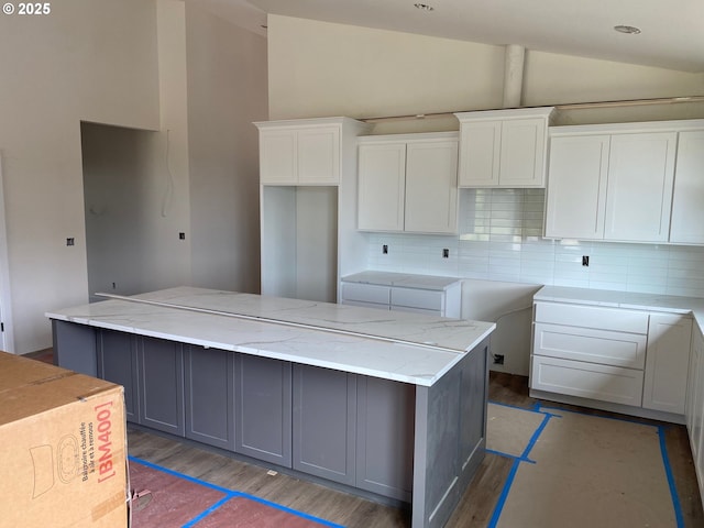 559 Meadows Dr, Manzanita, OR 97130 - kitchen with vaulted ceiling, tasteful backsplash, white cabinets, a center island, and light stone counters