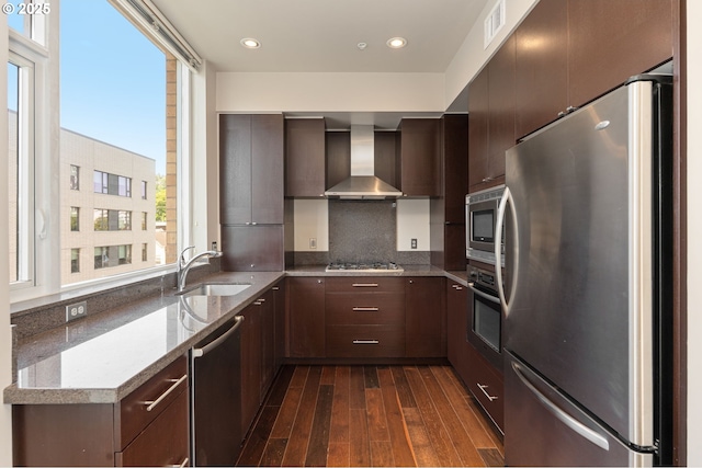 1930 S River Dr Unit W504, Portland, OR 97201 - kitchen featuring stainless steel appliances, wall chimney range hood, a sink, dark wood-style floors, and decorative backsplash