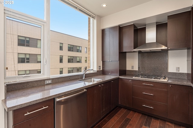 1930 S River Dr Unit W504, Portland, OR 97201 - kitchen featuring wall chimney range hood, appliances with stainless steel finishes, a sink, dark wood-style flooring, and backsplash