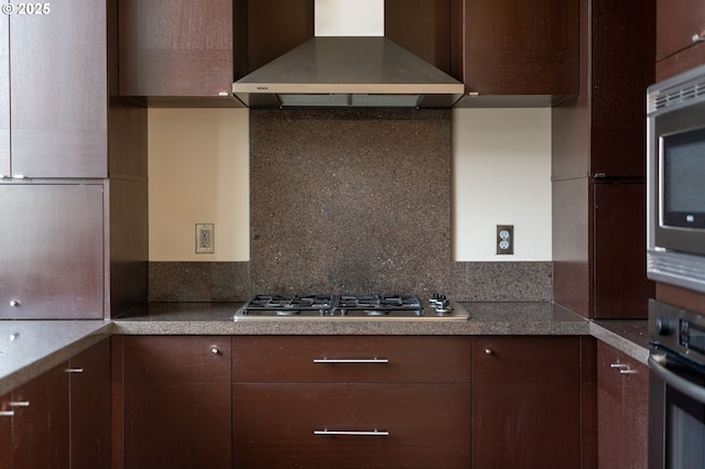 1930 S River Dr Unit W504, Portland, OR 97201 - kitchen featuring wall chimney range hood, stainless steel appliances, backsplash, dark brown cabinetry, and light countertops
