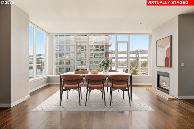 1930 S River Dr Unit W504, Portland, OR 97201 - dining space with baseboards, hardwood / wood-style floors, a glass covered fireplace, a city view, and a water view