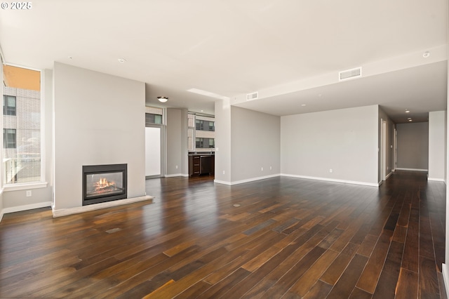 1930 S River Dr Unit W504, Portland, OR 97201 - unfurnished living room with dark wood-type flooring, a multi sided fireplace, and baseboards