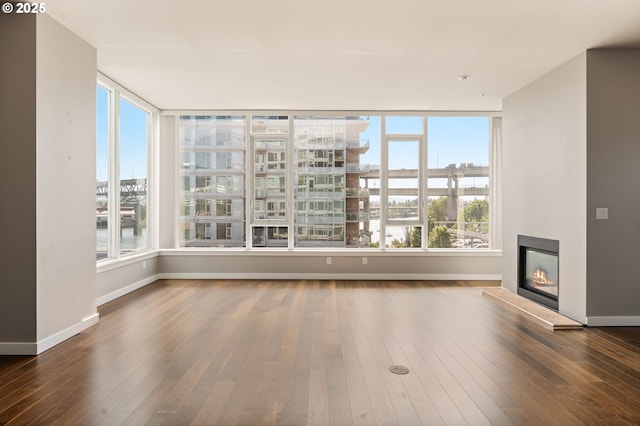 1930 S River Dr Unit W504, Portland, OR 97201 - unfurnished living room with hardwood / wood-style floors, baseboards, a glass covered fireplace, and a water view