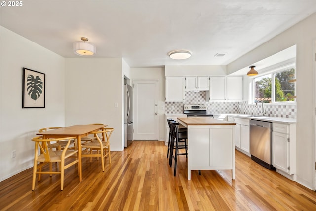 5515 SE 62nd Ave, Portland, OR 97206 - kitchen featuring stainless steel appliances, a sink, white cabinets, and backsplash
