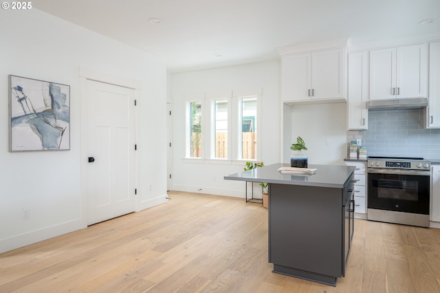 5827 NE 16th Ave, Portland, OR 97211 - kitchen featuring stainless steel electric stove, under cabinet range hood, light wood-type flooring, white cabinetry, and tasteful backsplash