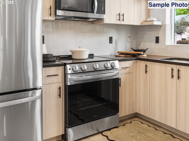 kitchen with decorative backsplash, light brown cabinets, dark countertops, modern cabinets, and stainless steel appliances