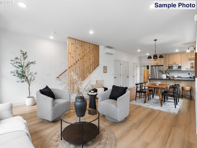 living area featuring stairway, light wood finished floors, an AC wall unit, and recessed lighting