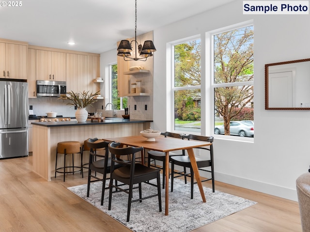 dining room with recessed lighting, baseboards, a notable chandelier, and light wood finished floors